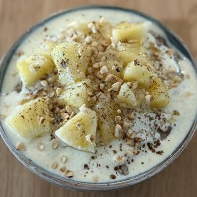 Schüssel Porridge mit Joghurt, Ananasstücken und gehackten Nüssen
