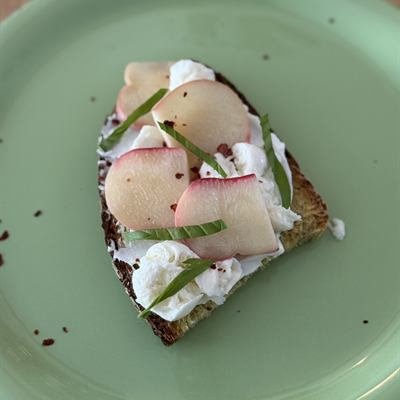 Brot mit Mozzarella und Pfirsichscheiben auf einem grünen Teller