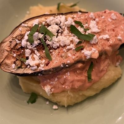 Gebackene Auberginenhälfte mit rosa Sahnesoße und Feta auf Kartoffelbrei