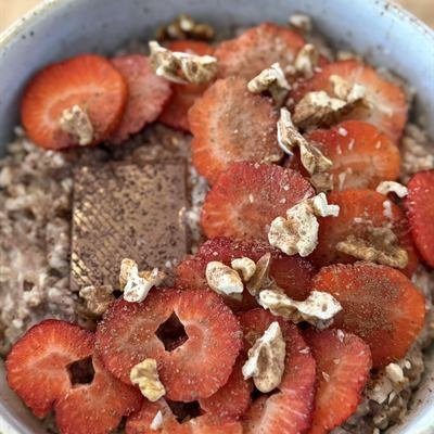 Porridge mit Erdbeerscheiben, Walnüssen und einem Stück Zartbitterschokolade
