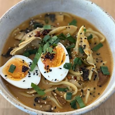 Ramen-Suppe mit Gyoza, halbiertem Ei und Frühlingszwiebeln
